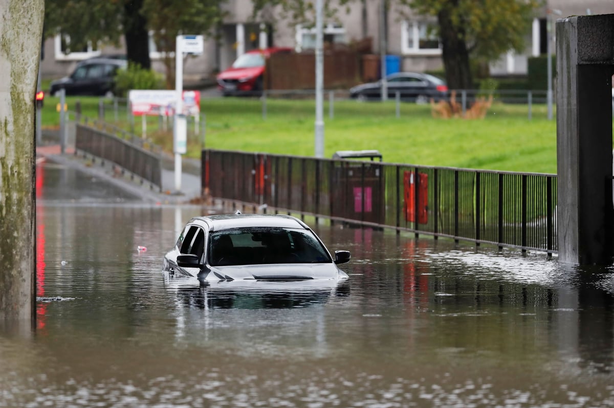 Carro rojo parcialmente sumergido en calle inundada